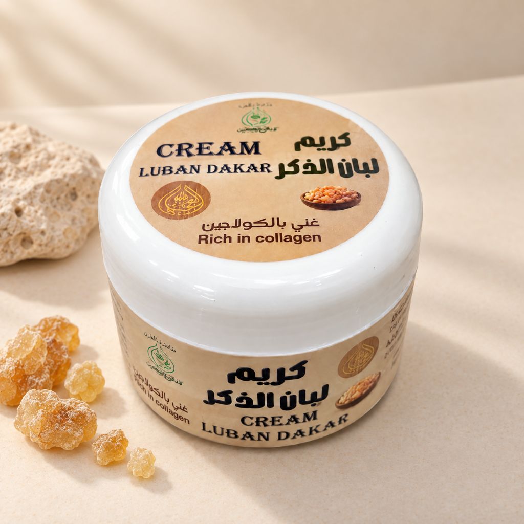 A white plastic jar of Luban Dakar Cream (Frankincense Cream) with a beige label, styled on a beige surface with a rock and gelatin pearls in the background.