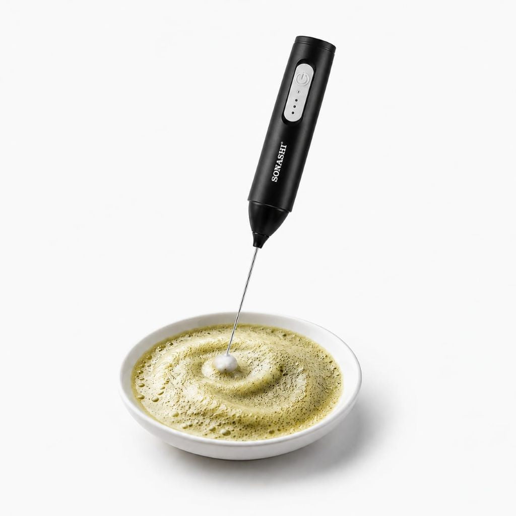 Black handheld milk frother / Powder Mixer stirring a bowl of green sidr powder on a white background