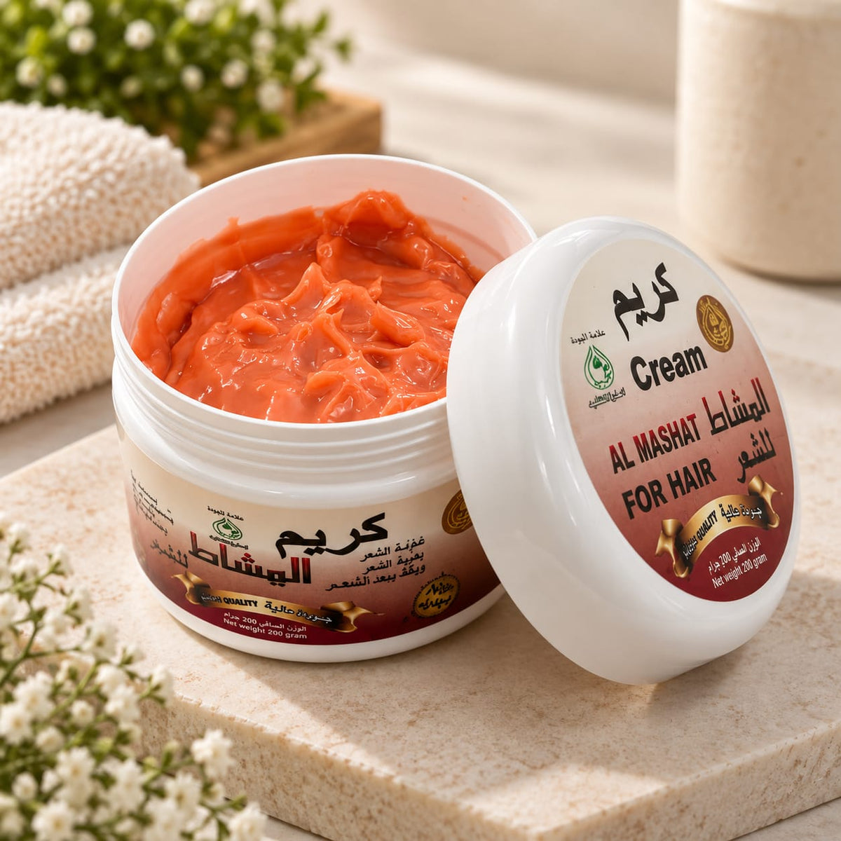 An open white jar of Al Mashat Cream for hair showing a thick orange-red cream inside, with the lid leaning beside it. The label includes Arabic text and 'Al Mashat Cream for hair'.