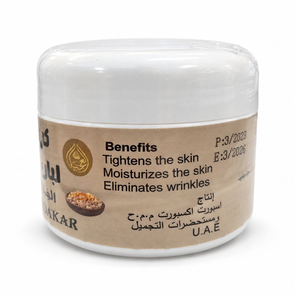 A white plastic jar of Luban Dakar Cream (Frankincense Cream) with a beige paper label. The label features English text detailing skin benefits and Arabic text, along with a small gold emblem and a picture of a walnut.